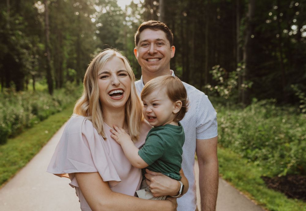 Candid family moments captured on a sunlit forest path.