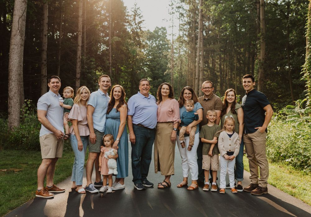 Family group poses together on a forest path during golden hour sunset.