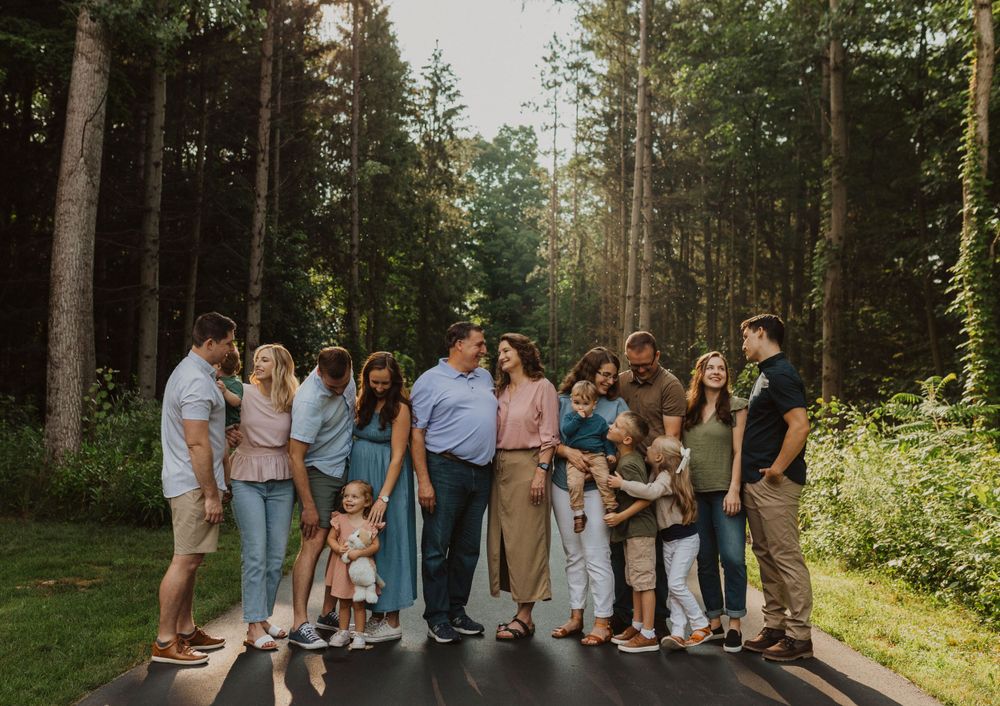 Large extended family gathering on a wooded trail in summer.