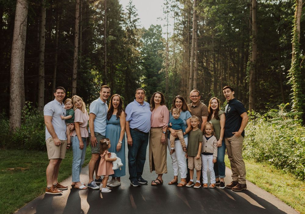 Multi-generational family portrait on tree-lined path with natural lighting.