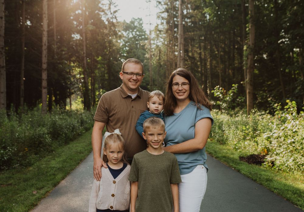 Family walking together on a tree-lined path during golden hour.
