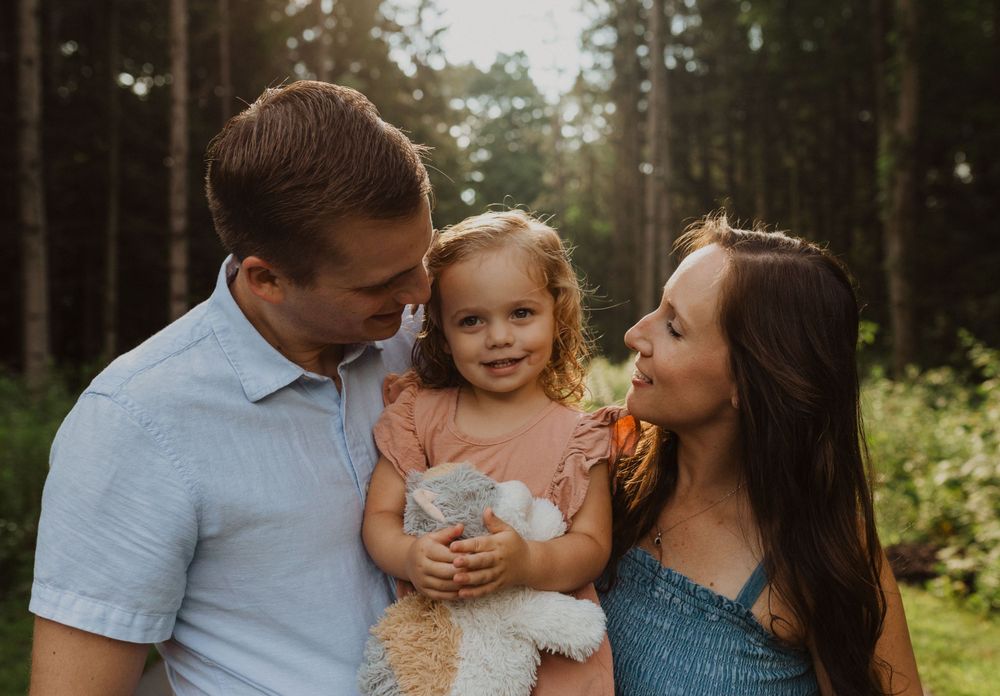 A candid family moment captured in a forest with warm lighting and natural expressions.