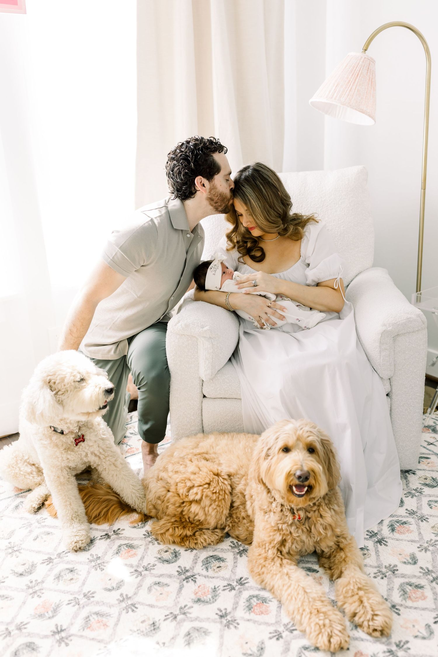Two golden dogs rest peacefully near a white armchair in a bright nursery setting.