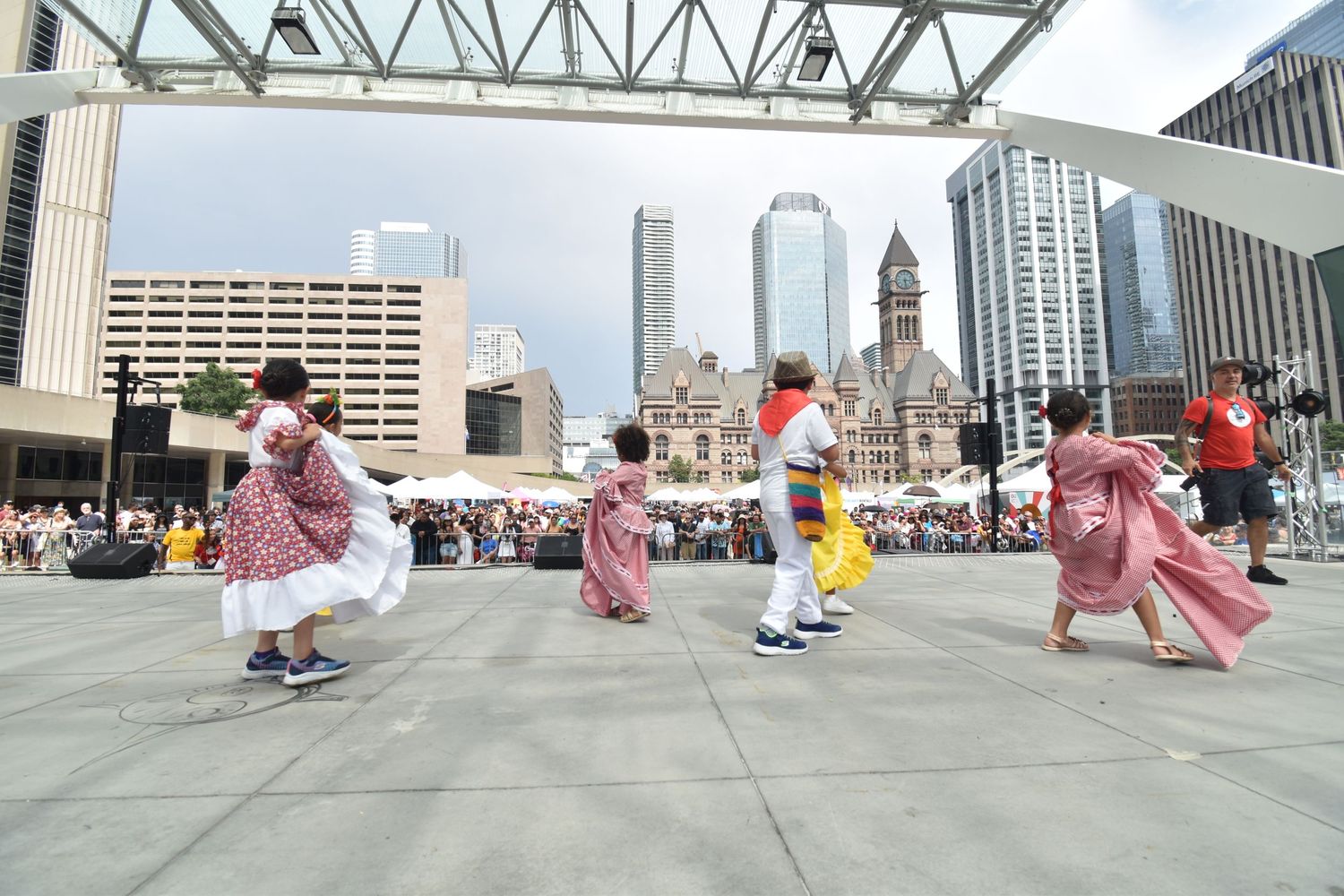 Traditional folk dancers perform in colorful dresses at an outdoor urban festival plaza. Toronto GTA
