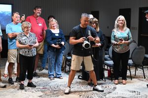 Group of adults holding cameras at an indoor photography workshop or class in a community center.