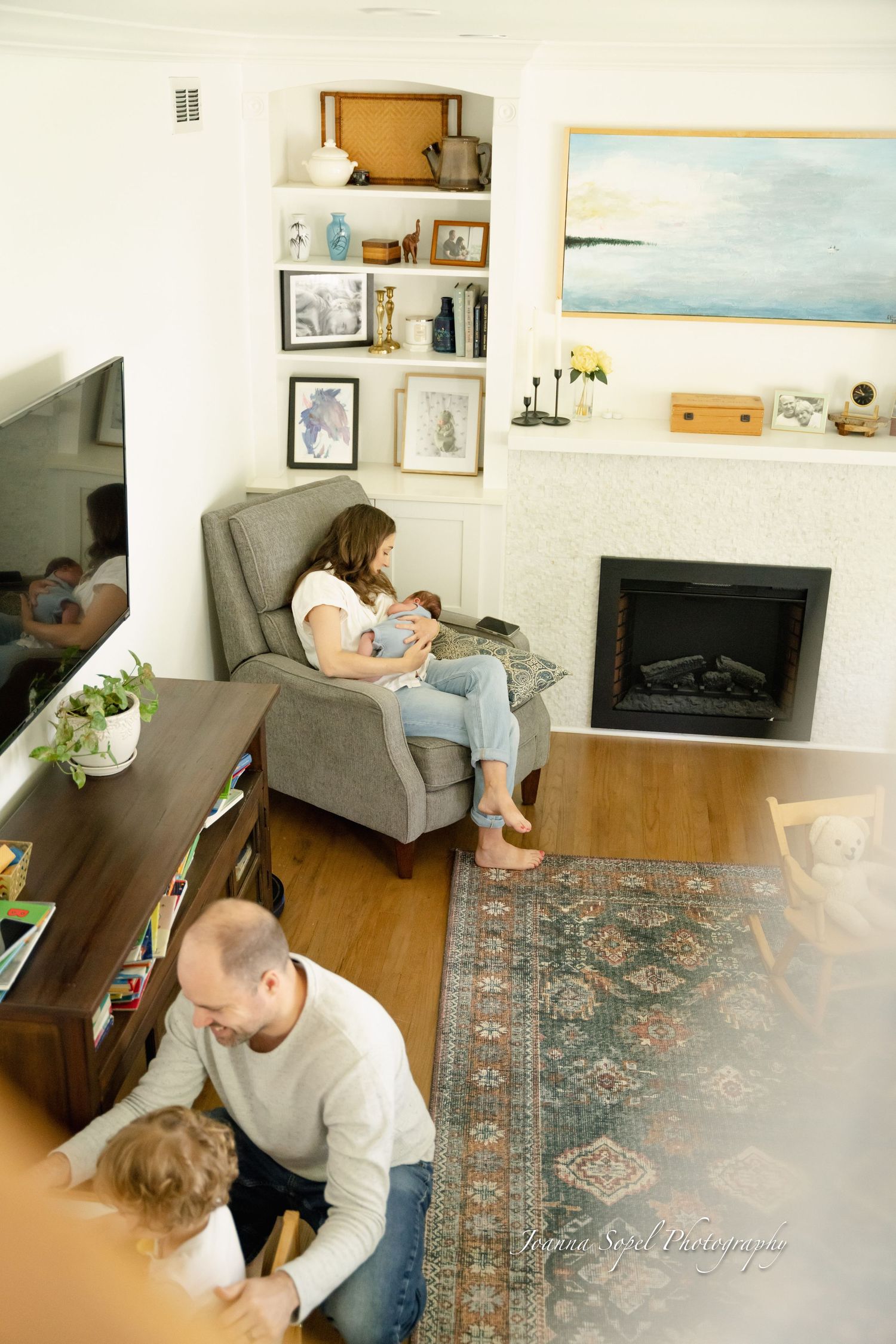 Family relaxes together in cozy living room with modern fireplace and patterned area rug st lifestyle newborn session in Mount Prospect