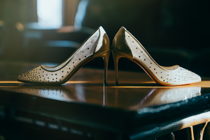 Elegant white leather brogue high heel wedding shoes with perforated details photographed in dramatic lighting.