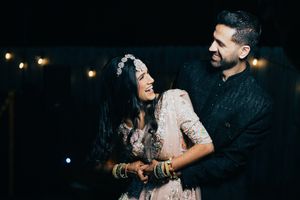A couple in Houston shares an intimate dance moment during their Sangeet ceremony in a dimly lit venue with string lights.