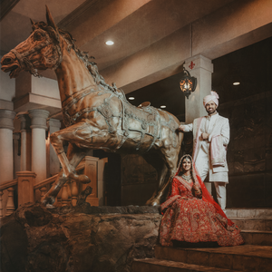 A Houston couple in traditional wedding attire poses dramatically in a dimly lit artistic space.