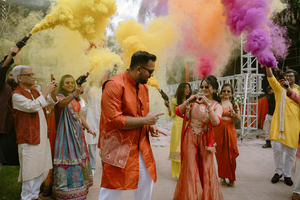 People celebrating with colorful powder during a festive Holi celebration in traditional Indian attire.