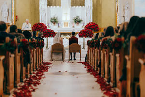 A Lake Placid, NY church aisle decorated with red poinsettias and wedding decor leading to a brightly lit altar.