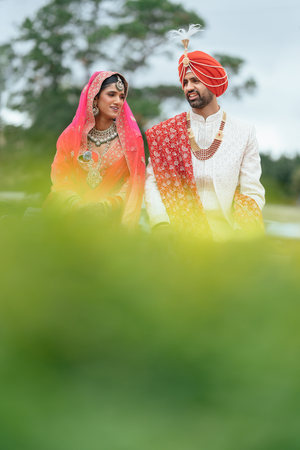 Traditional Sikh wedding couple in Houston in colorful attire pose together outdoors on their Gurdwara wedding day.