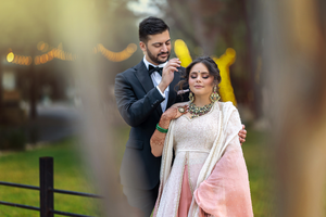 Romantic couple moment captured outdoors with traditional South Asian wedding attire.