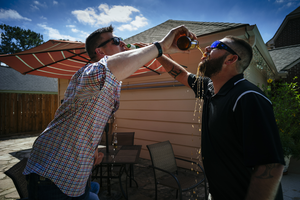 Groom and best man pouring beer playfully on each other.
