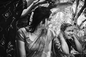 Candid black and white photo capturing joyful laughter and celebration during a cultural haldi ceremony.