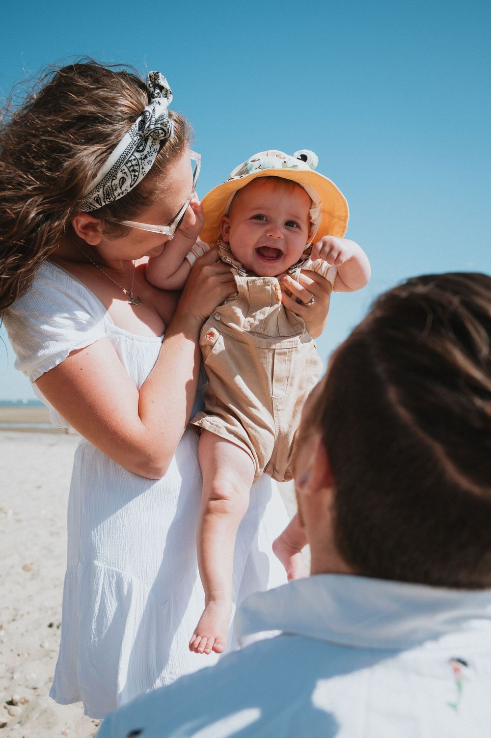 A family shares a tender moment on a bright sunny day as they play and laugh together at the beach.