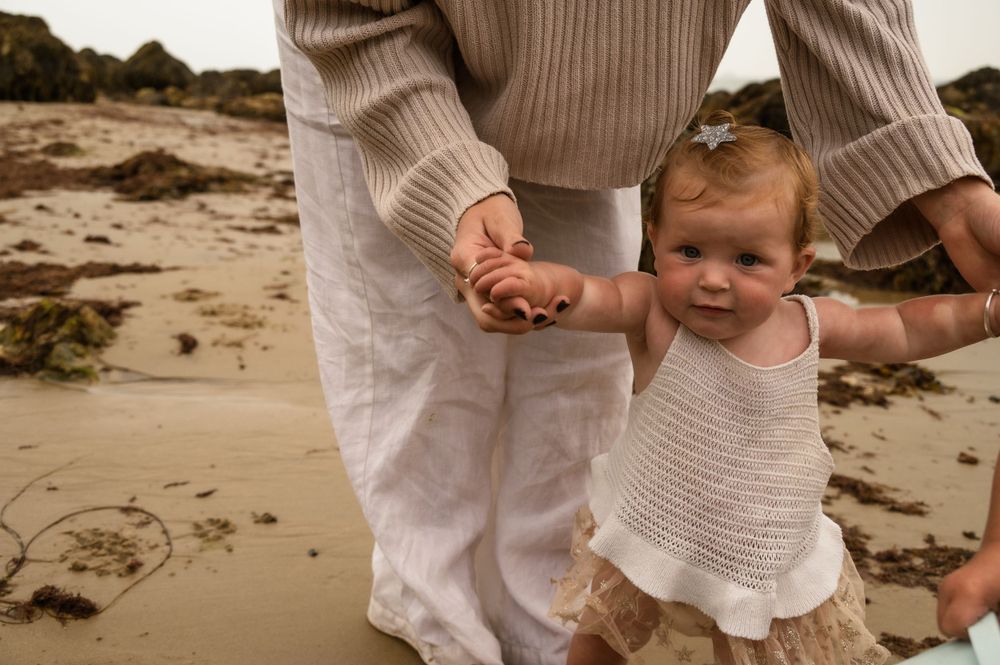 Close-up shot of hands holding while walking on sandy beach.