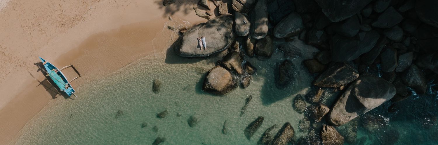 Aerial view of a boat near rocky coastline with turquoise waters.