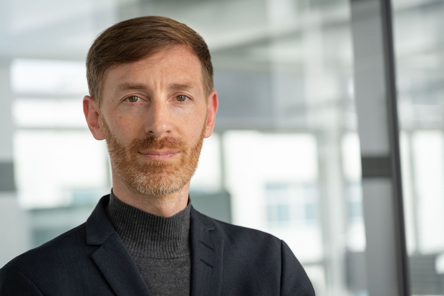 Professional portrait in a modern office space with bright natural lighting.