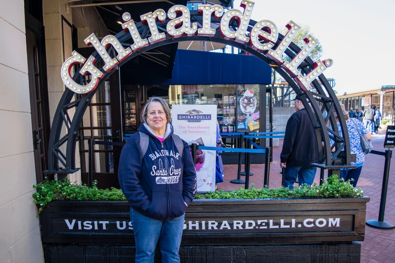 Exterior view of a Ghirardelli chocolate shop storefront with illuminated signage.