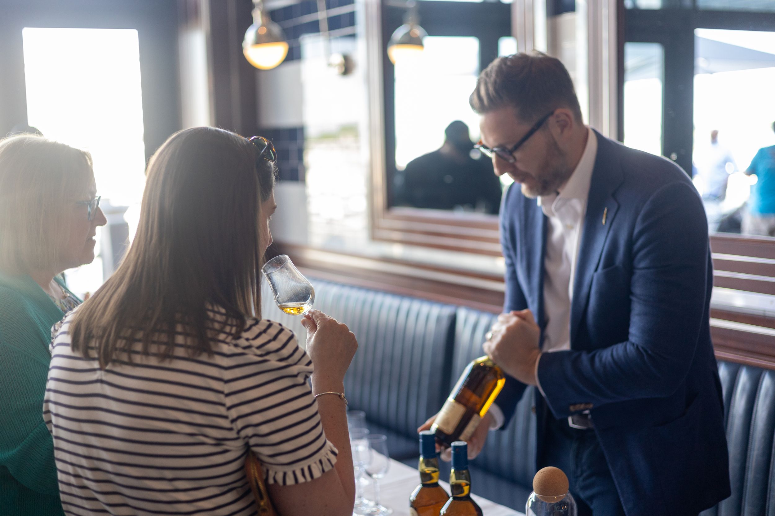 Staff member pouring wine for customers at an upscale restaurant.