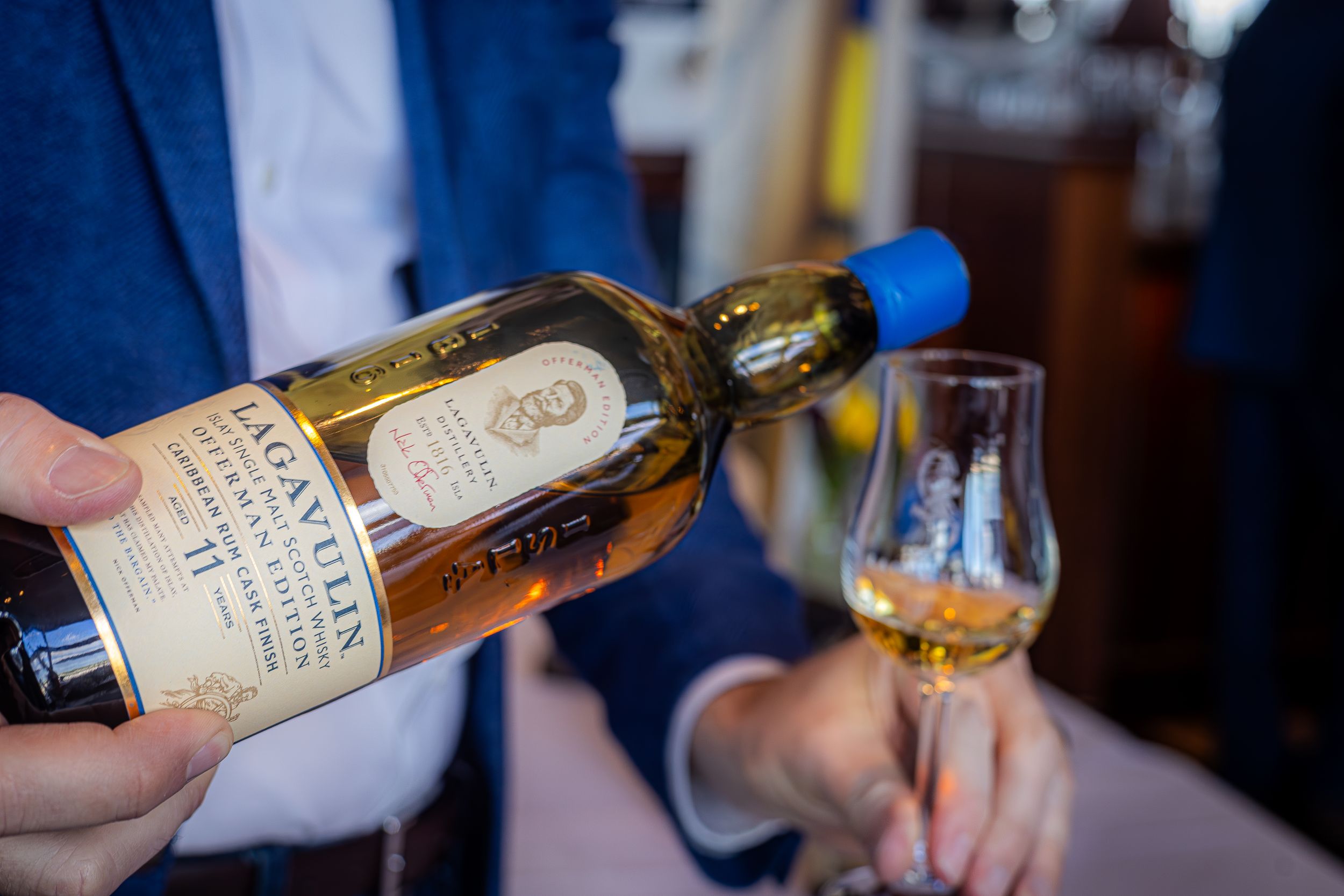 Close-up of someone pouring aged whiskey into a tasting glass.