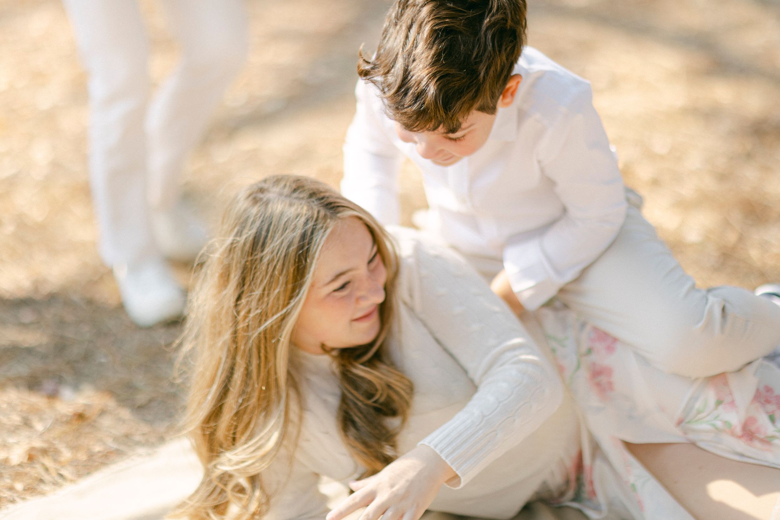 A dreamy outdoor photoshoot in soft natural light with people dressed in white sitting on the ground.