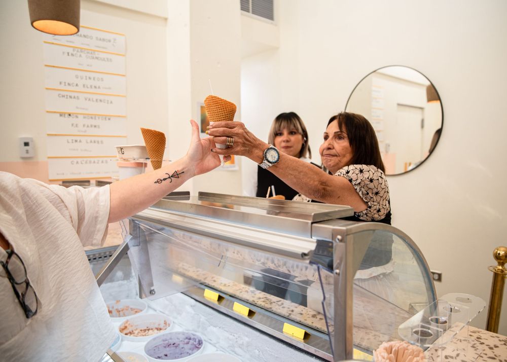 People toast with drinks across a service counter in a modern cafe setting.
