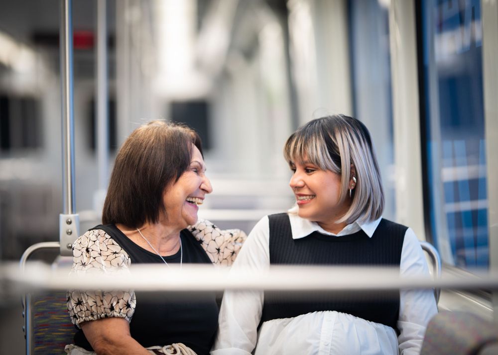 Two people share a joyful moment while sitting together on public transit.