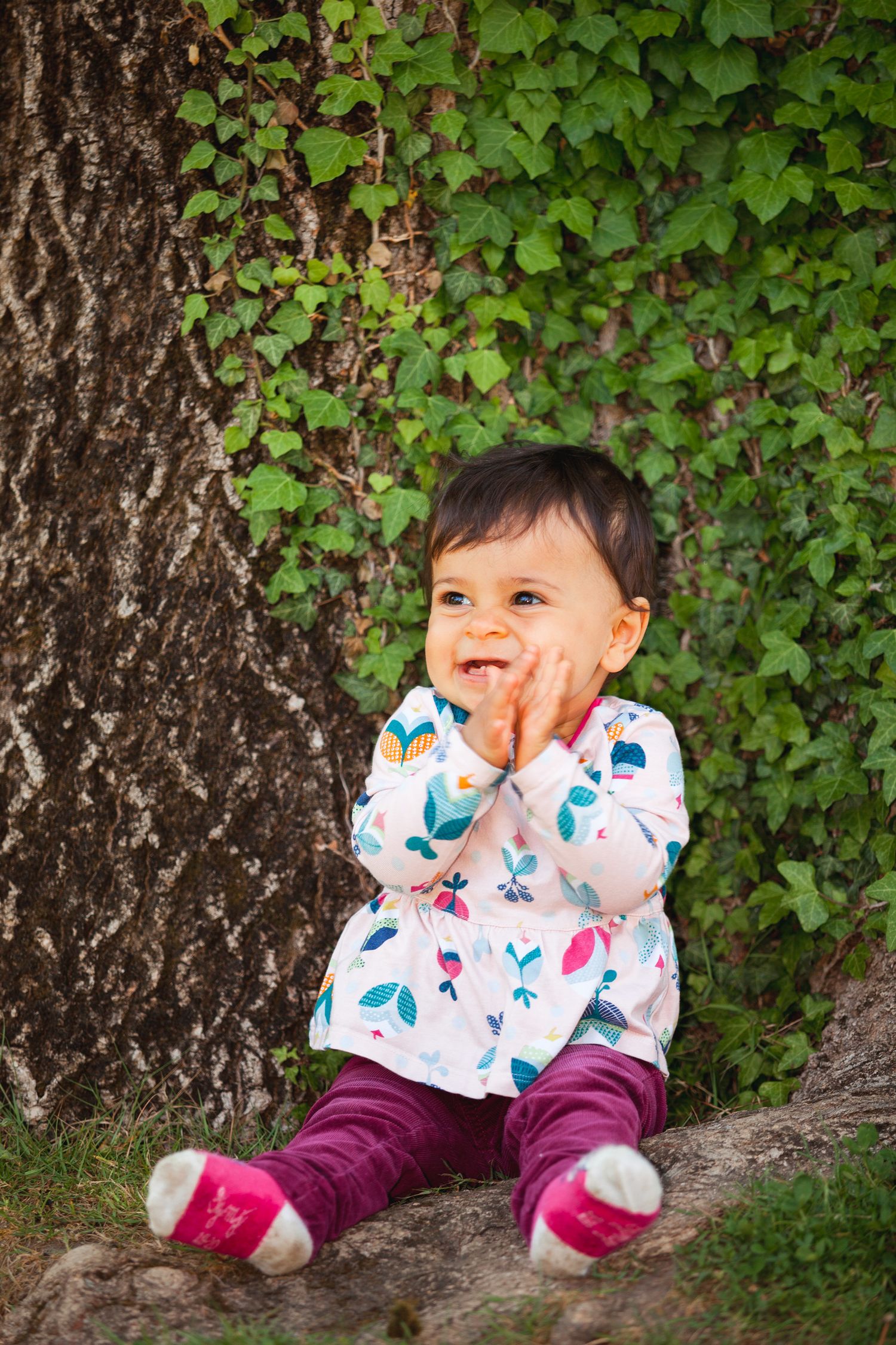 Un bébé assis contre un tronc d'arbre du Jardin des Plantes de Grenoble