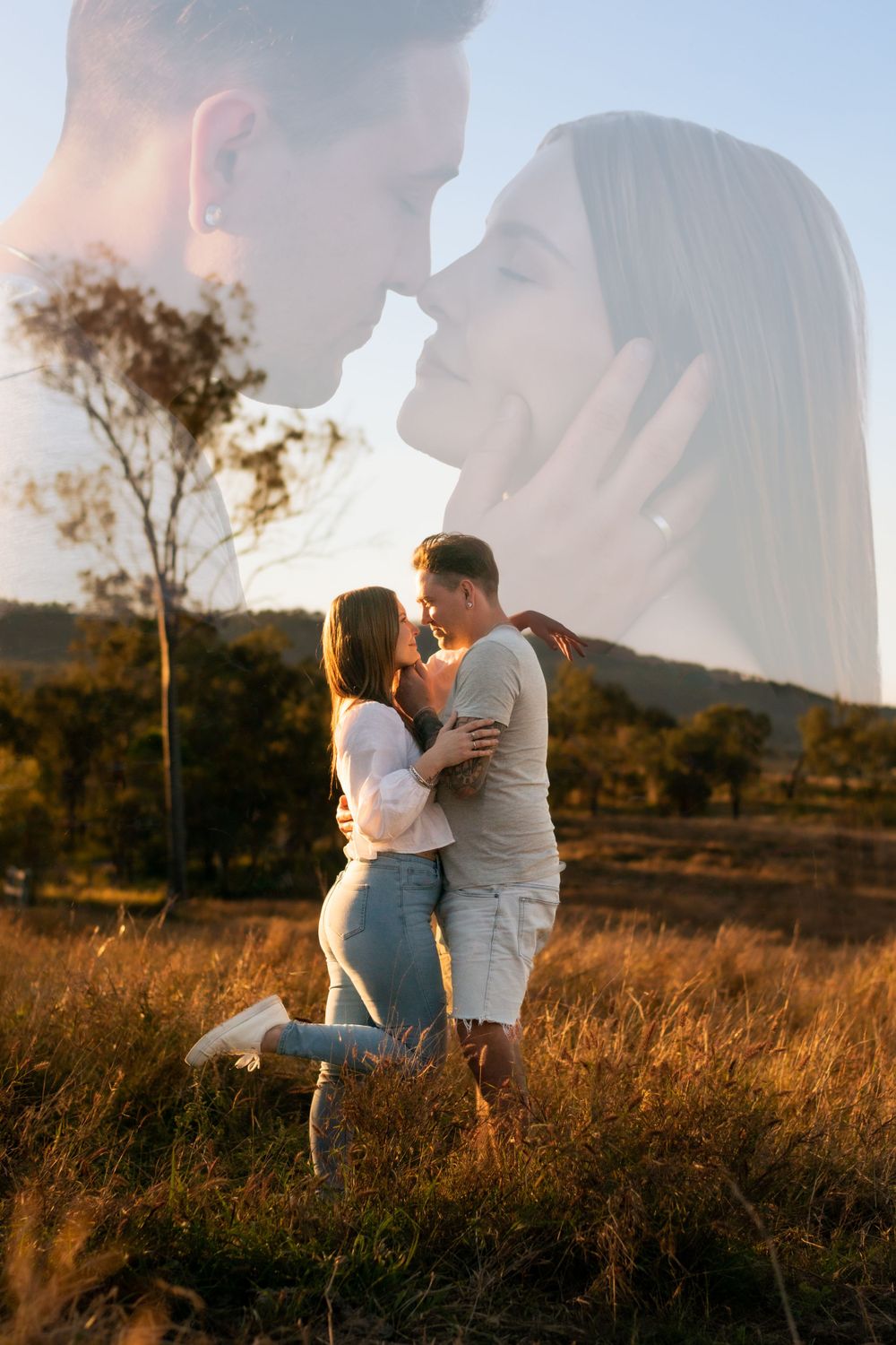 Double exposure photo of couple kissing against scenic countryside backdrop at sunset.