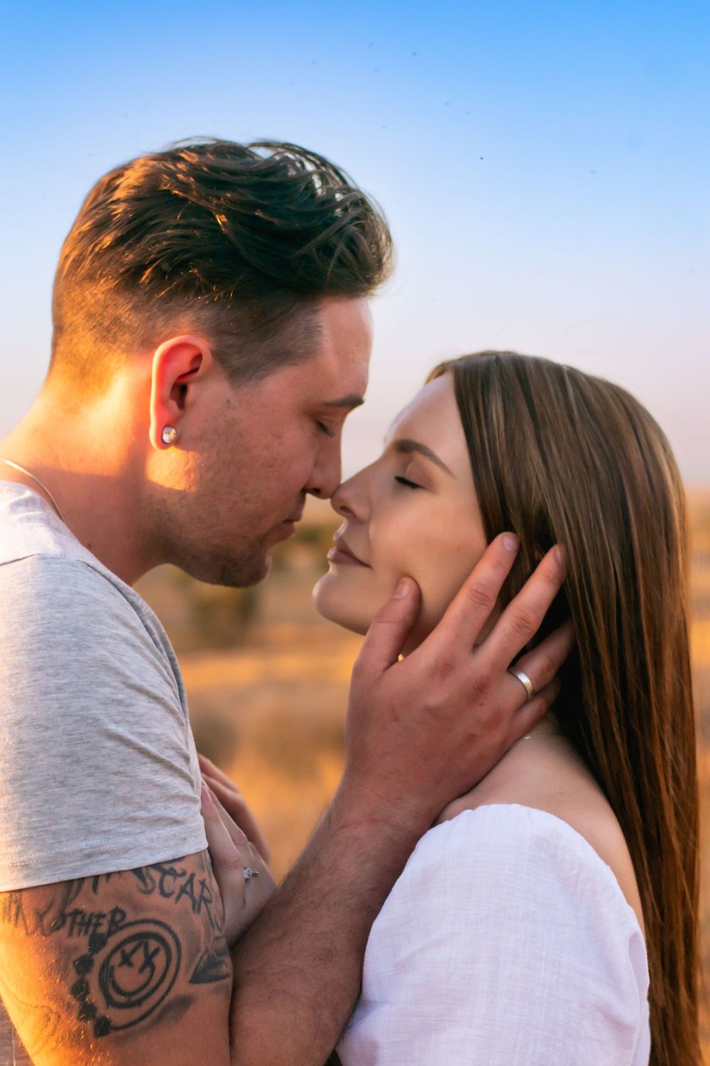 Intimate couple sharing tender moment during golden hour outdoors.