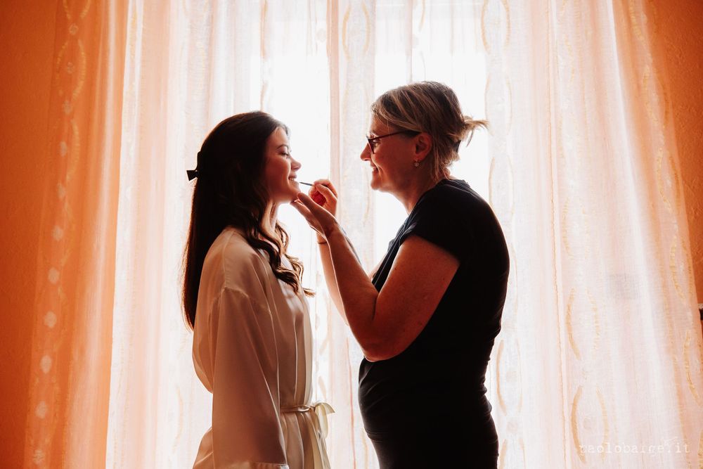 Silhouette of two people against sheer curtains in warm lighting.