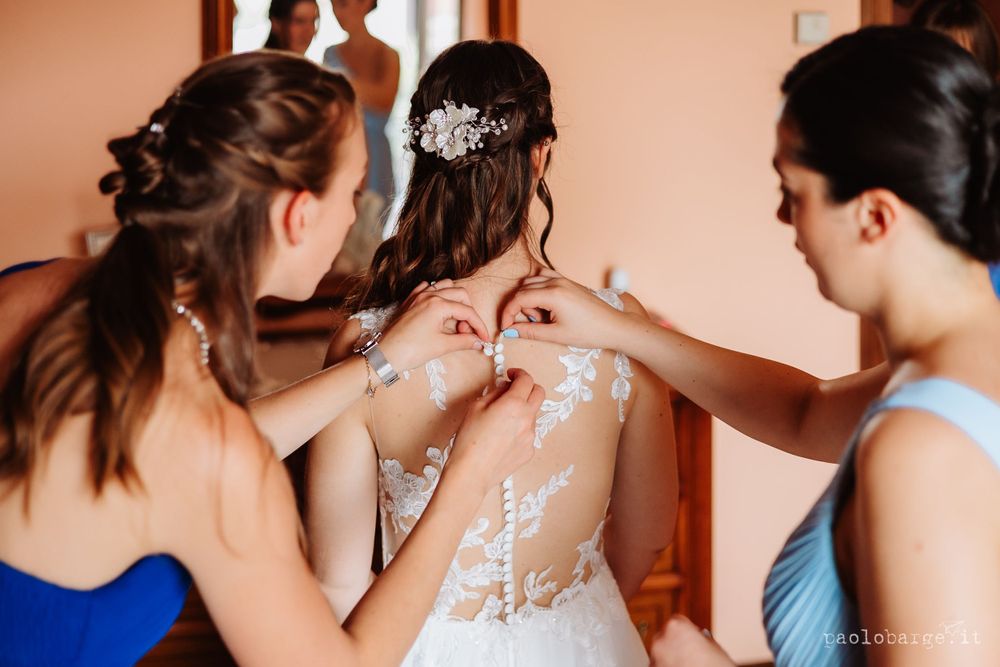 Close-up of intricate lace detail being adjusted on a wedding dress.