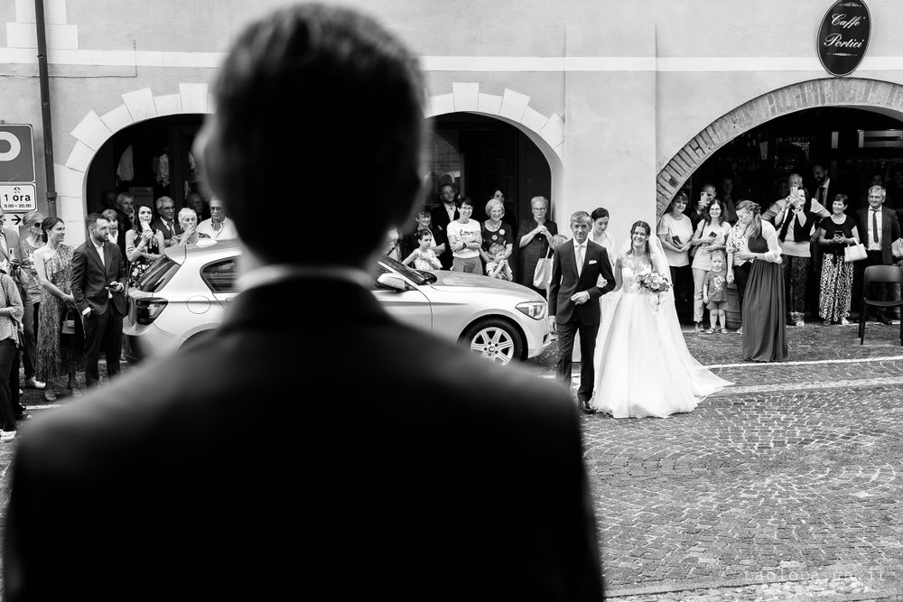Black and white photo of wedding guests gathered outside historic arched buildings.
