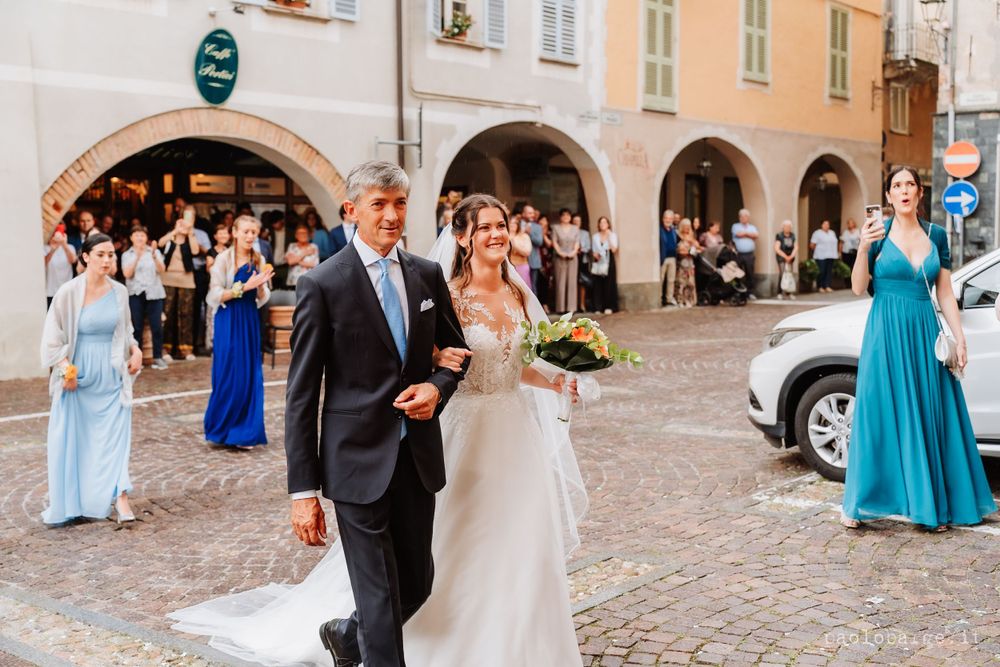 Wedding party walks through a European town square with bride in white gown.
