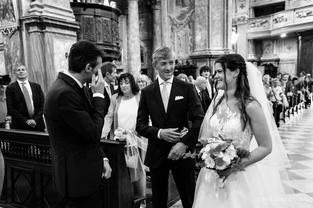 Black and white photo capturing an intimate wedding ceremony inside an ornate church.
