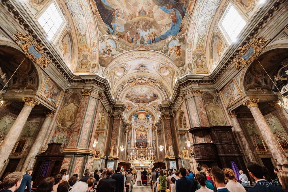 Ornate baroque church interior with painted ceiling frescoes and marble columns.