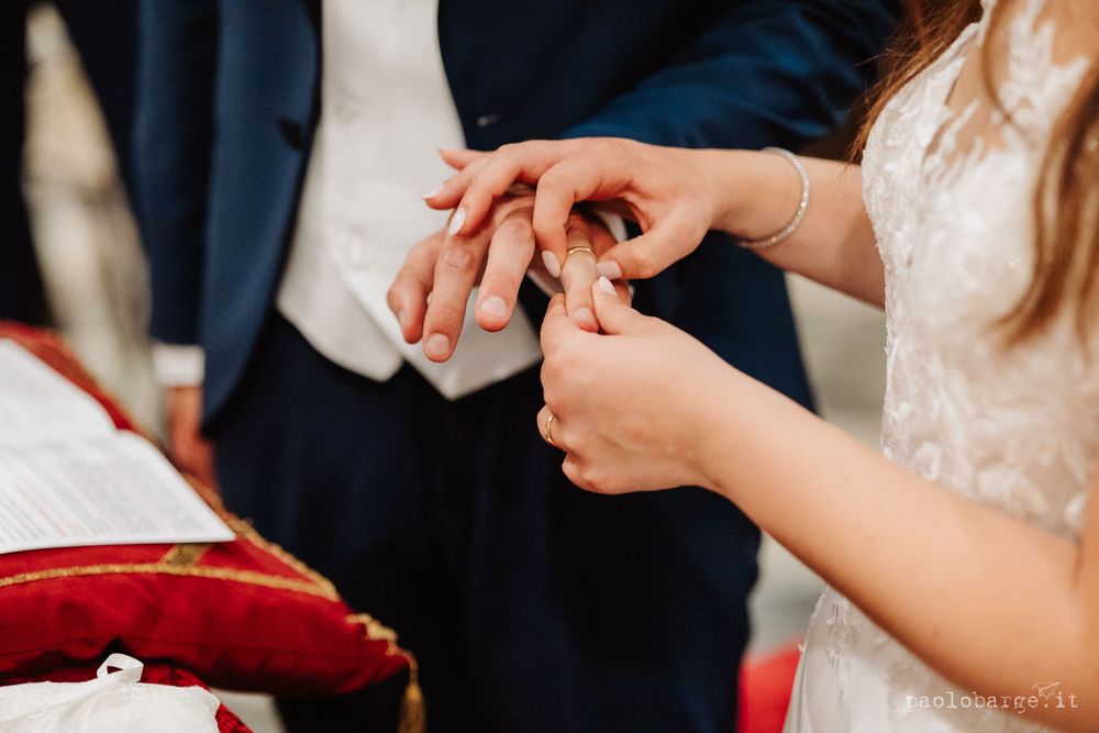 Close-up of hands exchanging wedding rings during ceremony.