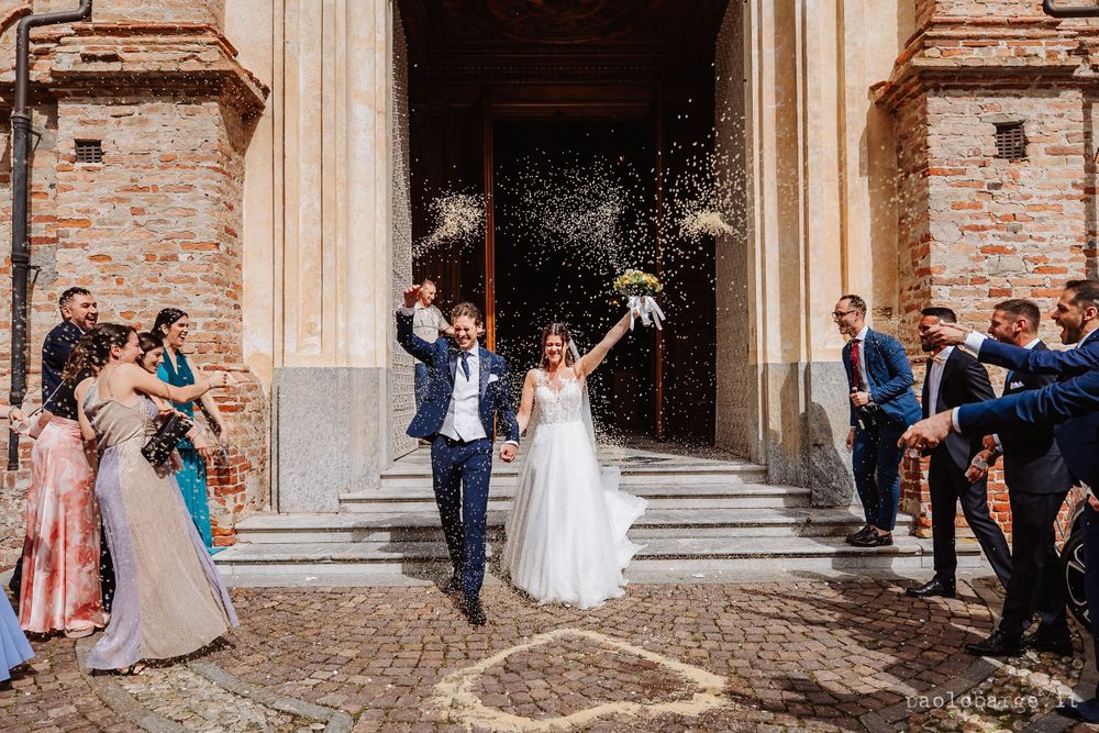 Newlyweds exit church as guests throw confetti on church steps.