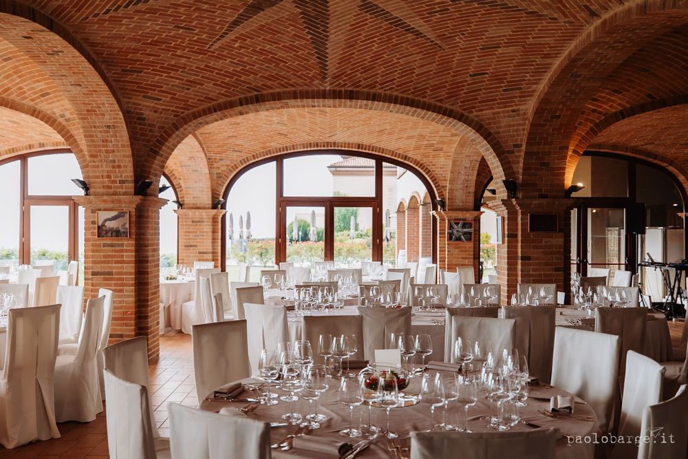 Elegant wedding reception venue with brick arches and white-covered tables set for dining.