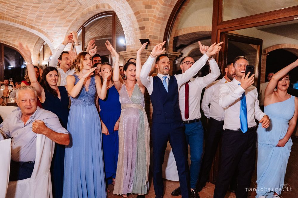 Wedding party dances and celebrates under brick archways at reception.