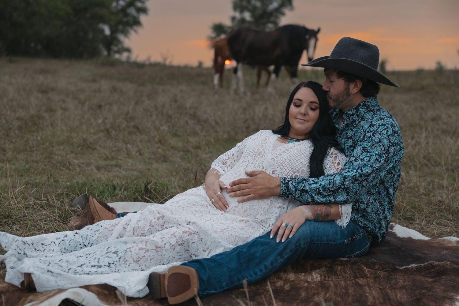 Western maternity photography session featuring couple in client closet dress with horses in background during golden hour Garrison, ND
