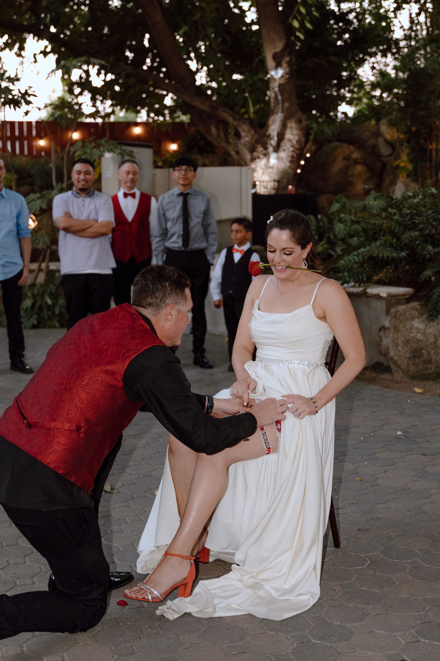 A couple performs a playful dance move in formal attire at an outdoor reception.