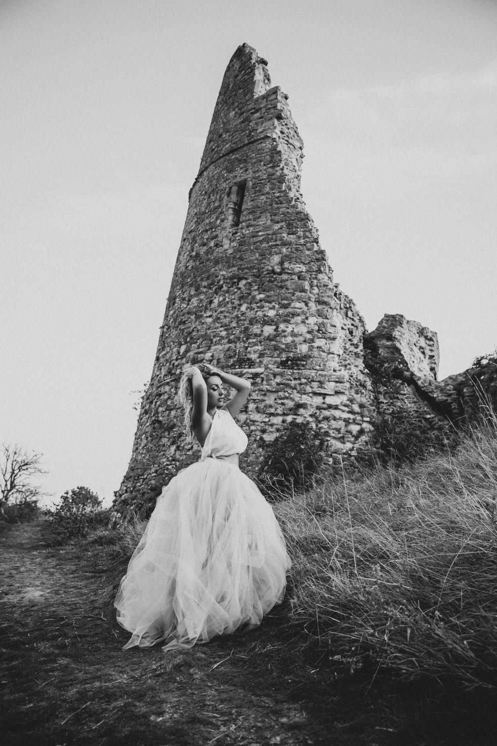 Beautiful girl dressed in blue and purple hue dress with Hadleigh Castle in background black and white