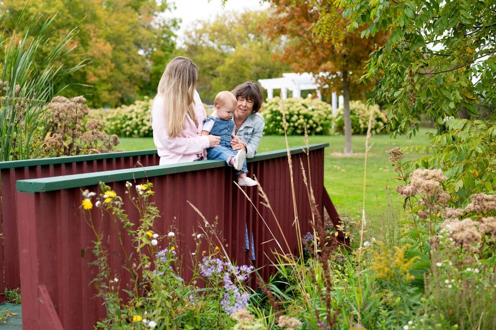 People enjoy a romantic moment in a lush garden setting with red fencing and vibrant greenery in the background.