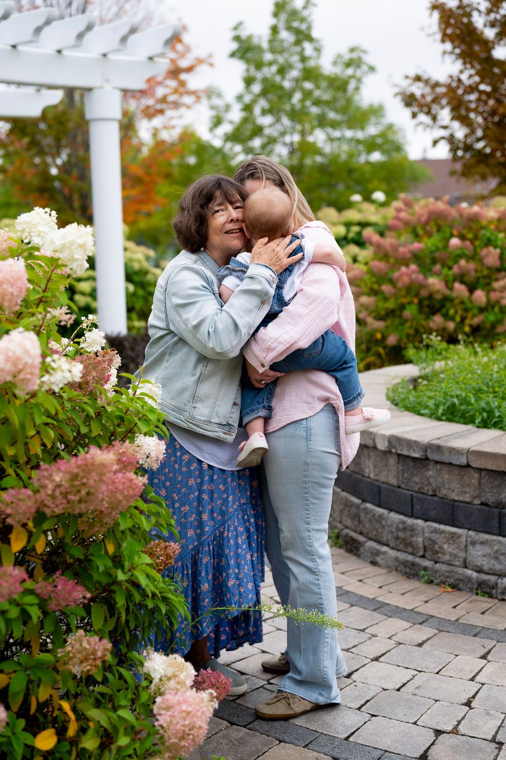 A joyful moment shared between people in a garden with blooming hydrangeas and a stone patio.