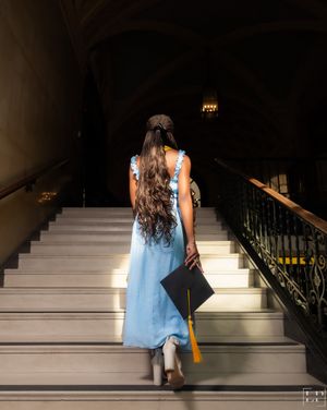 Person in light blue dress ascending white marble stairs in dramatic lighting.