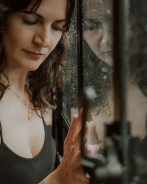 Artistic portrait series showing reflective poses through glass with moody lighting and double exposure effects.