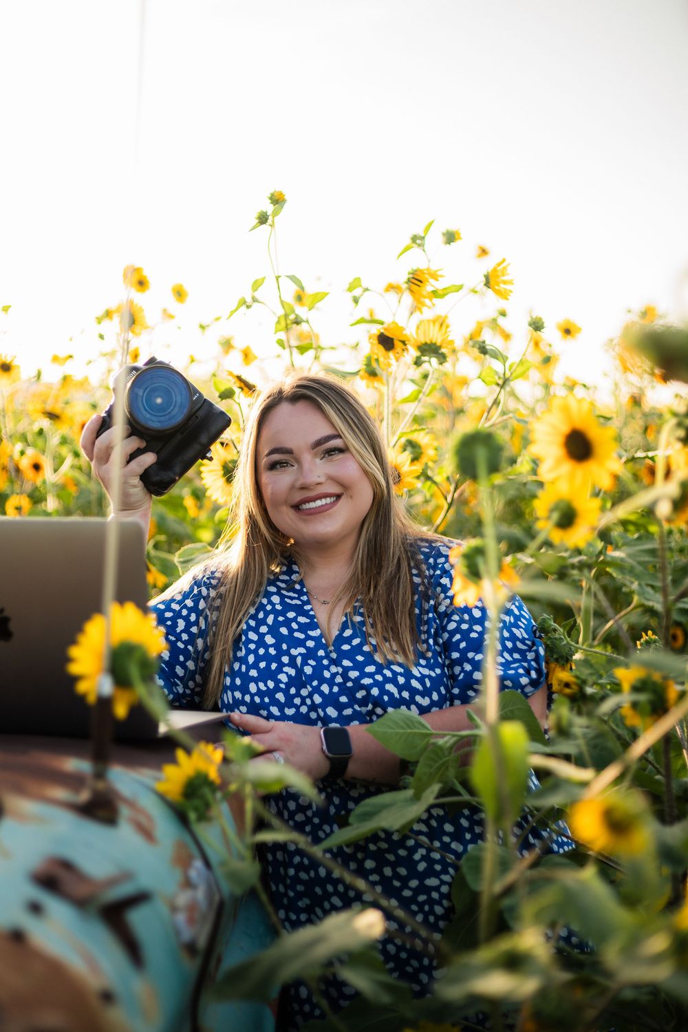 Photographer in a lace top captures photos in a wildflower meadow.